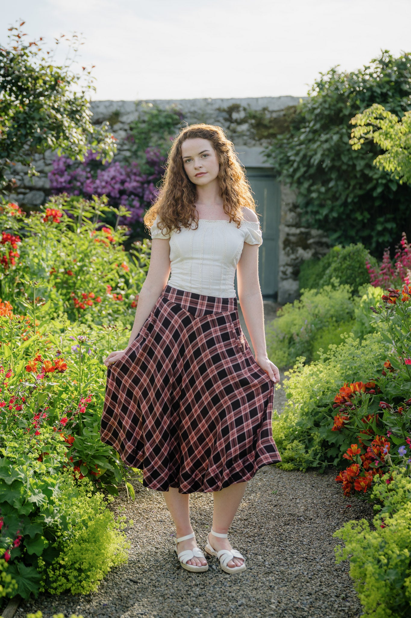 Cottagecore plaid midi skirt with pockets, a flattering high waist and flowing silhouette, styled in a colourful summer flower garden.