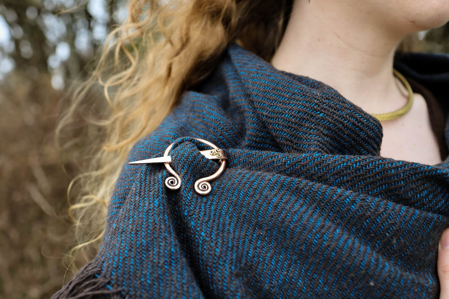 Close-up of black and turquoise handwoven wool shawl with Uisneach copper brooch showing texture and pin detail