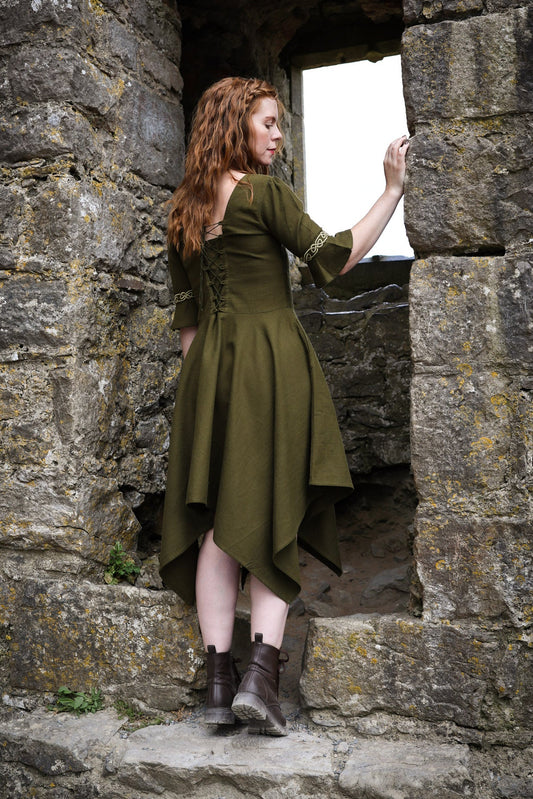 Back view of green Macha folklore dress showing the lace-up corset back, fitted bodice and pointed handkerchief hem skirt.