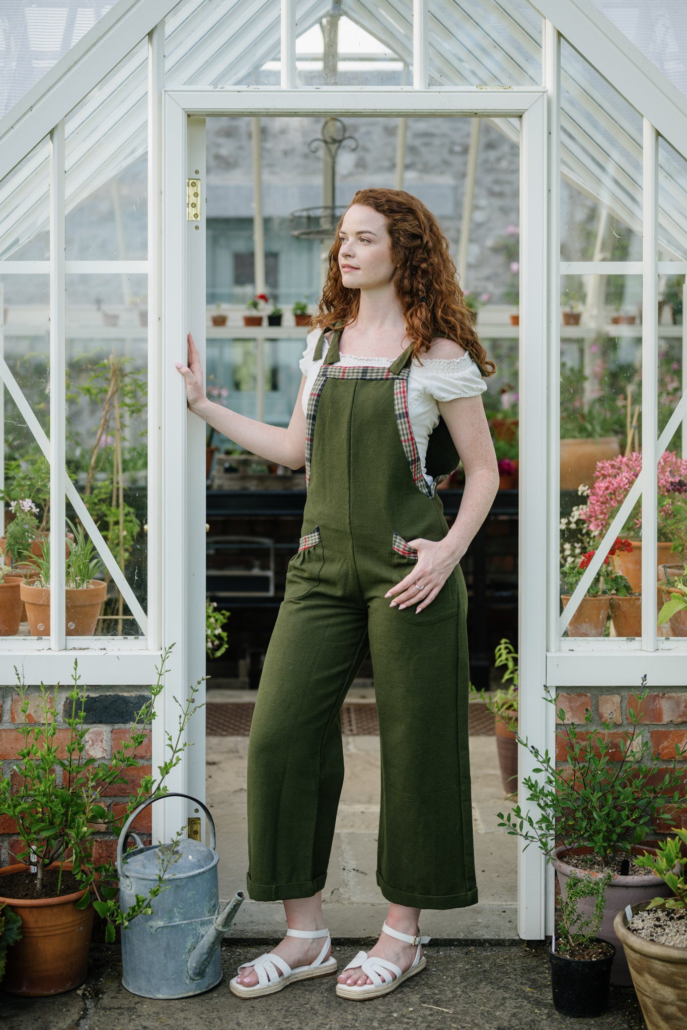 Adjustable Green Dungarees styled in a greenhouse doorway with wide leg fit and checked trim details