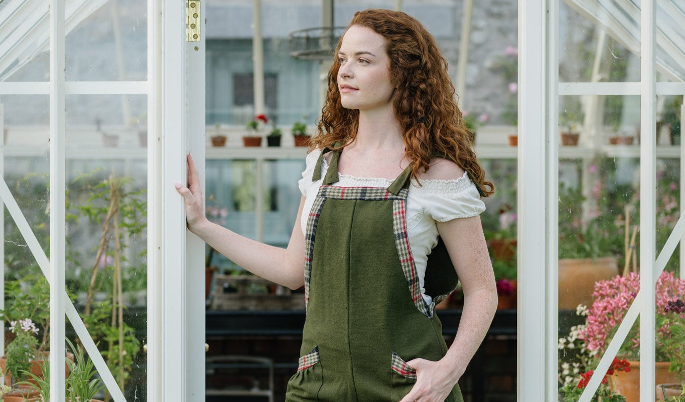 Adjustable Green Dungarees styled in a greenhouse doorway with wide leg fit and checked trim details