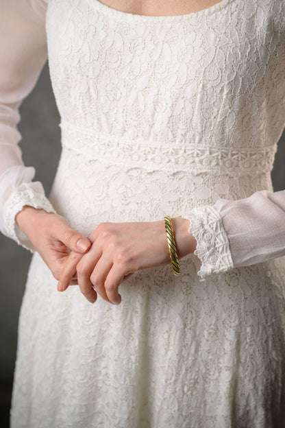 Close-up of Annagh Celtic wedding dress in cotton lace with sheer sleeve cuff, scalloped trim and delicate waist detail