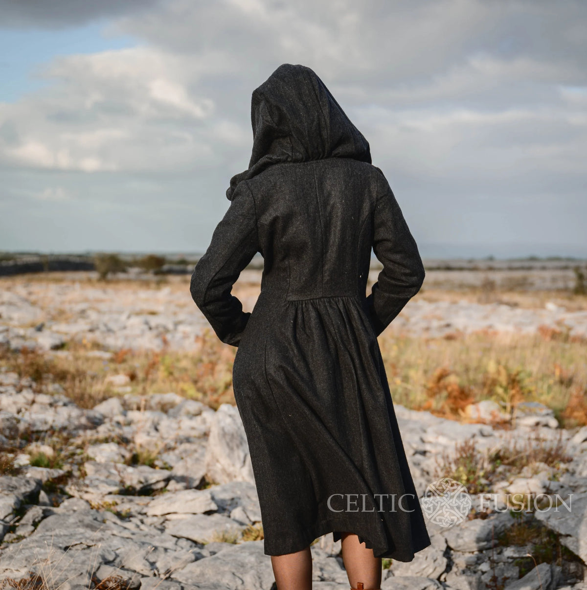 Back view of black Princess wool coat showing oversized hood, tailored bodice and gathered full skirt
