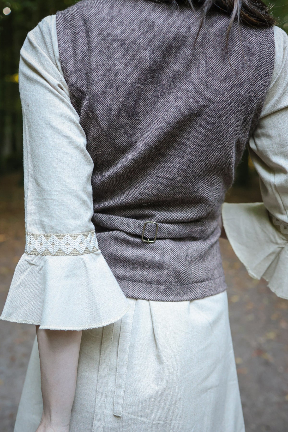 Back view of women’s brown tweed vest showing fitted tailoring and buckle back strap
