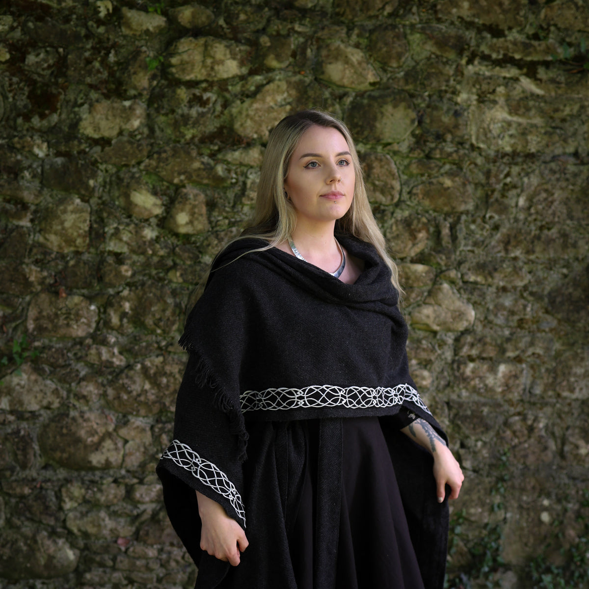 Black Celtic wool cape styled as a shoulder wrap showing embroidered knotwork trim and fringed edge Celtic clothing
