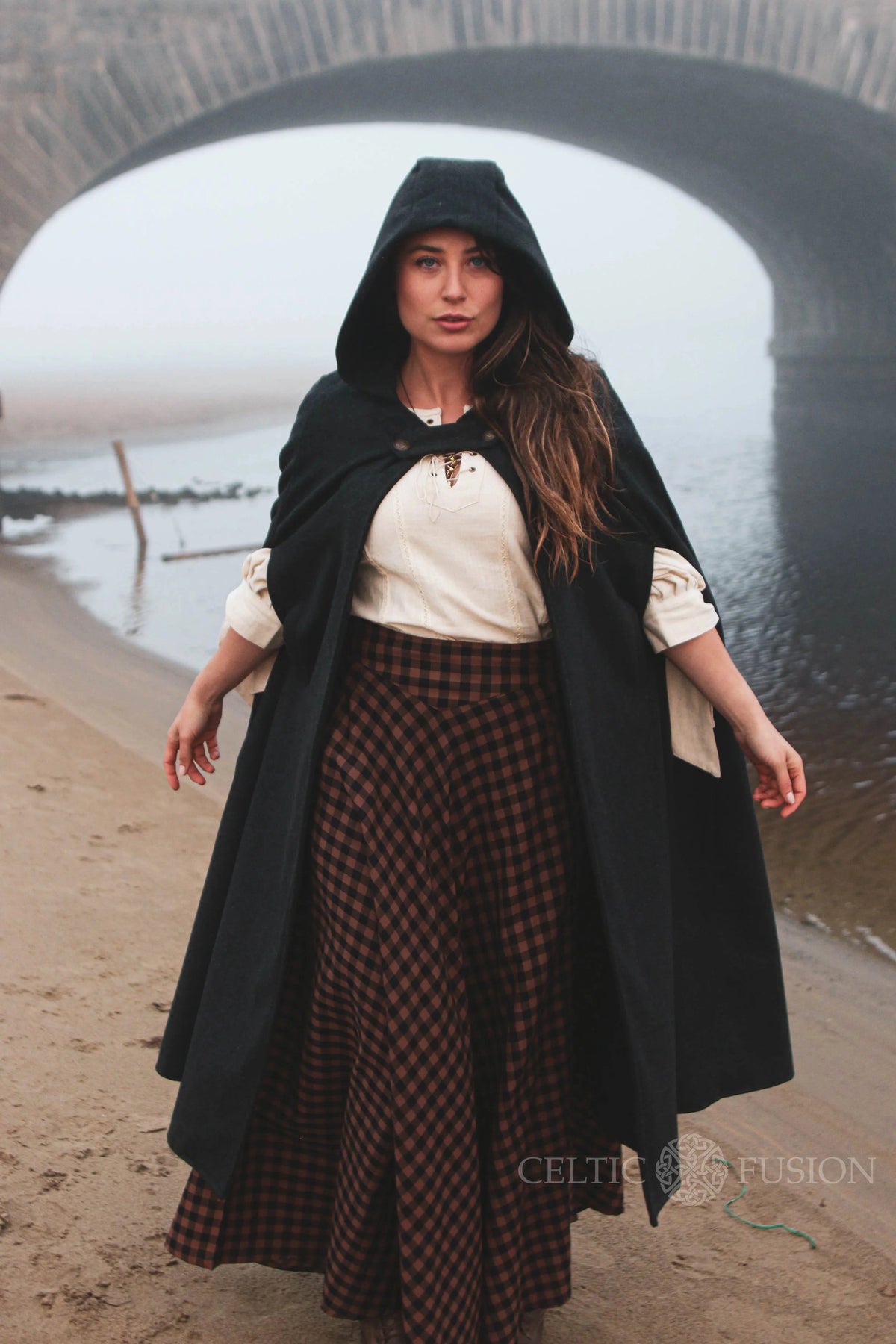 Black gothic medieval wool cloak with hood, pockets and long flowing silhouette worn outdoors