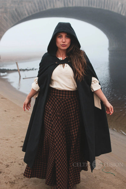 Black gothic medieval wool cloak with hood, pockets and long flowing silhouette worn outdoors