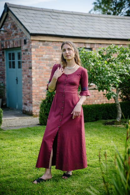 Burgundy Celtic maxi dress with Celtic embroidered sleeves styled in a cottage garden setting