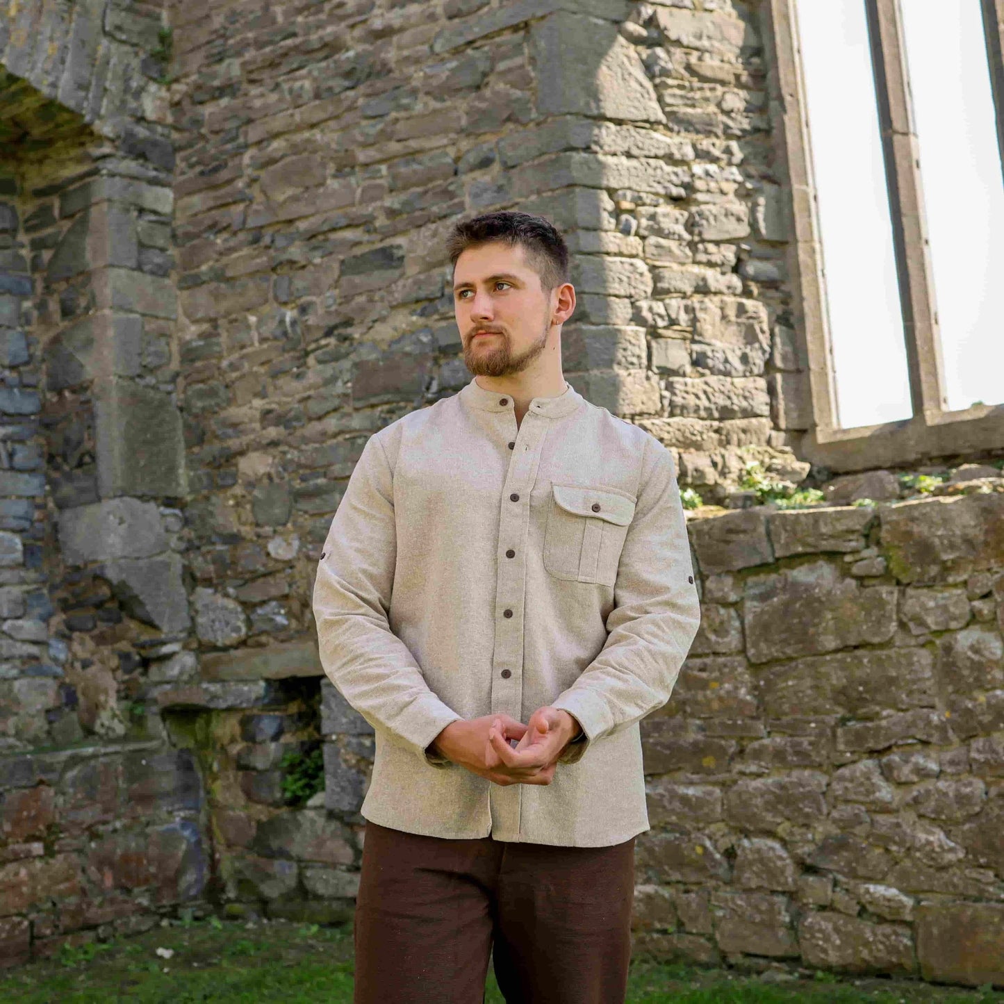 Celtic collarless dress shirt for men in beige, styled outdoors with long sleeves and heritage-inspired tailoring