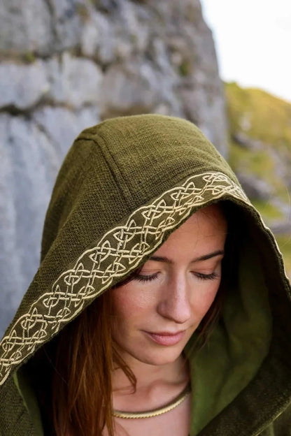 Close-up of olive green Celtic hooded jacket showing golden knotwork embroidery around the deep hood.