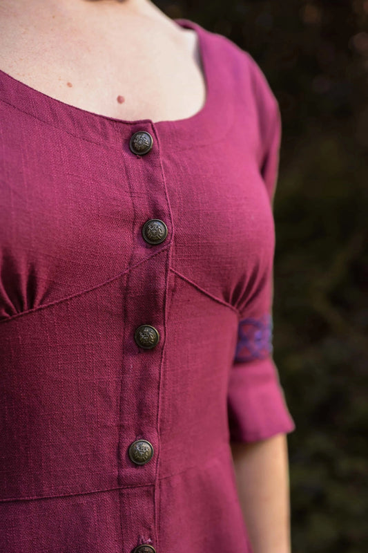 Close-up of button front burgundy folklore dress showing scoop neckline and fitted bodice detail