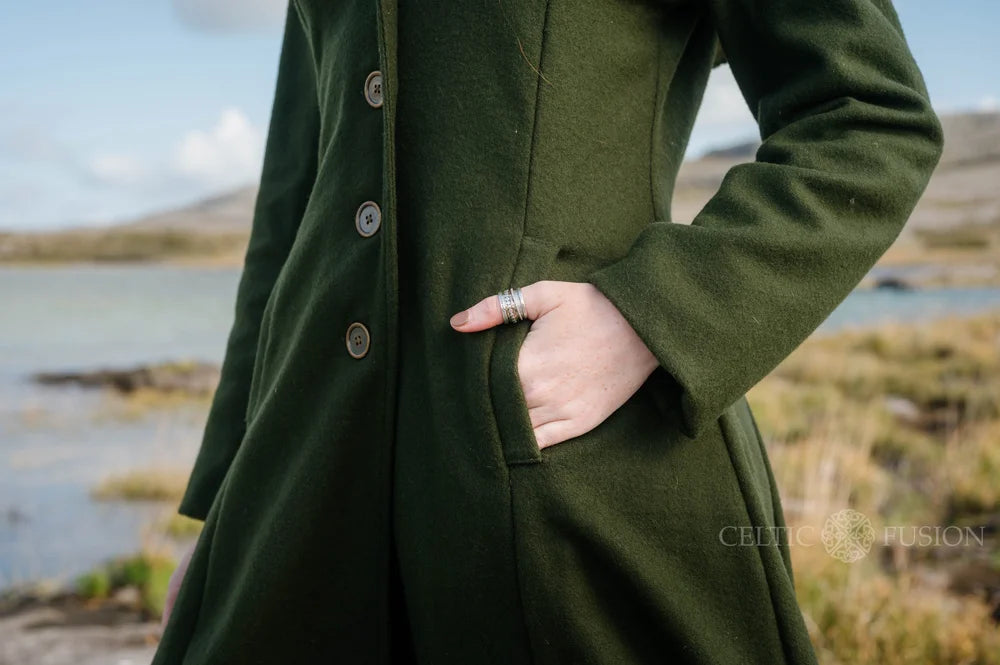 Close-up of forest green hooded wool coat showing practical side pocket, tailored seams and button fastening