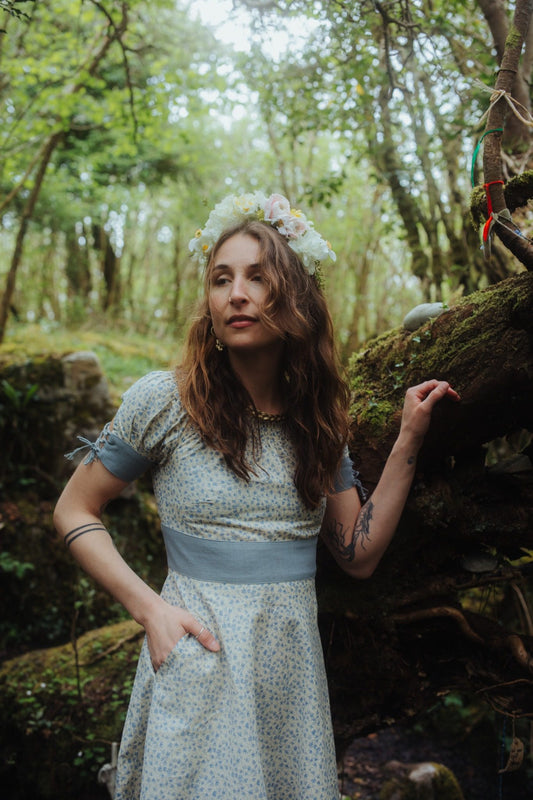 Forget Me Not Linen Dress in blue floral linen blend fabric, styled in a hazel woodland with flower crown and Celtic jewellery.