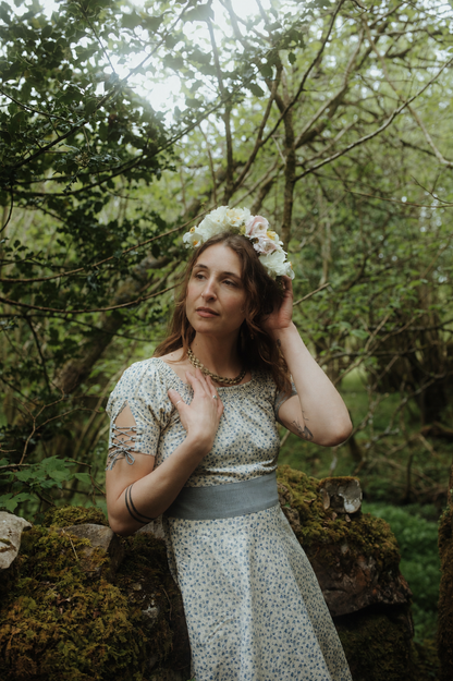 Garden party wedding guest dress in blue floral linen blend fabric, styled with a flower crown in an Irish woodland setting.
