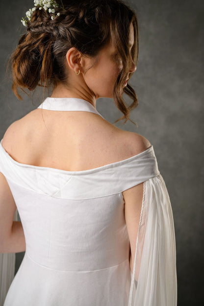 Close-up of ivory wedding dress back with off shoulder detail, halter neckline and chiffon draped sleeve