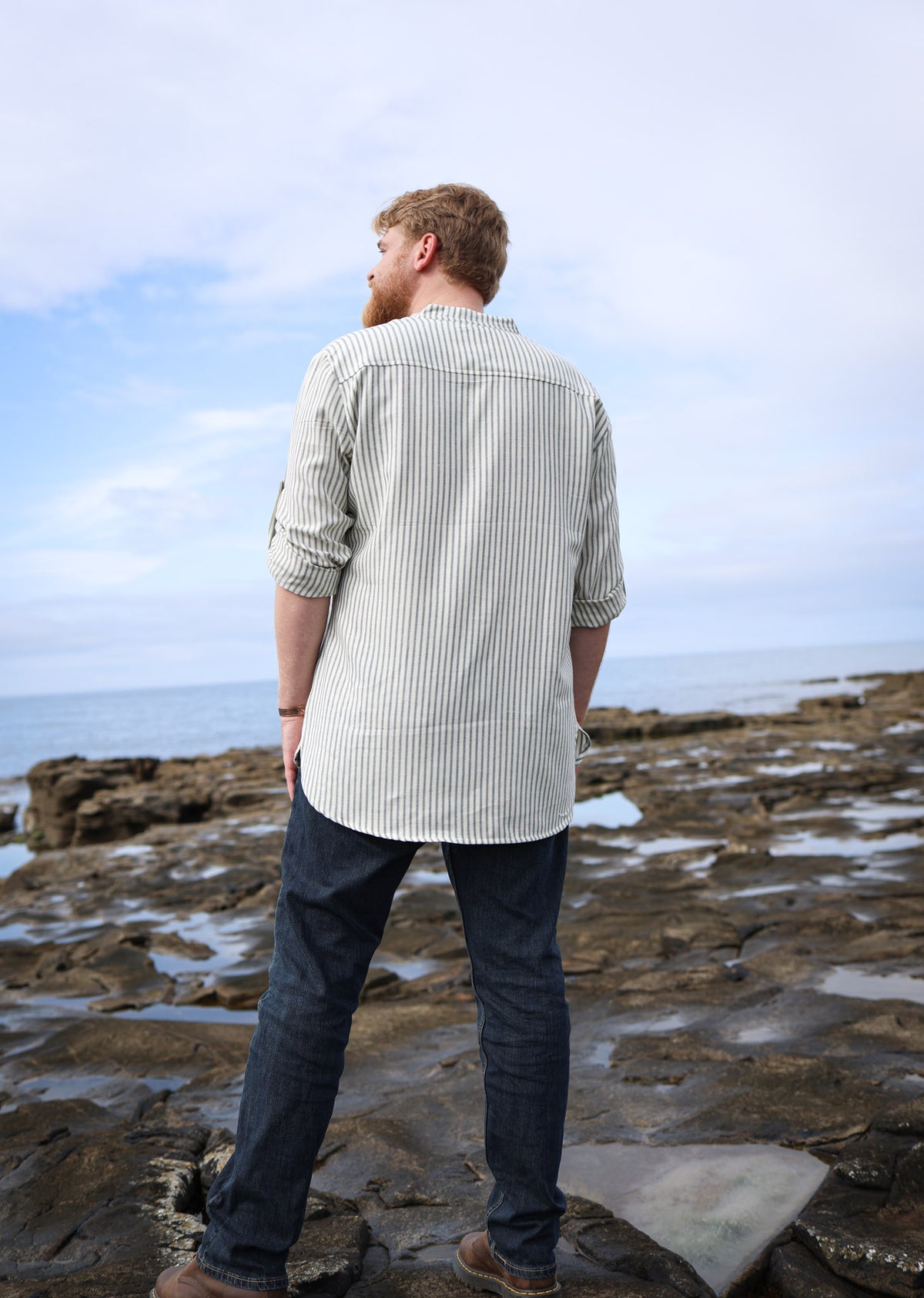 Men’s striped grandfather collar shirt in cream and blue cotton, shown from the back with rolled sleeves and a relaxed longline fit.
