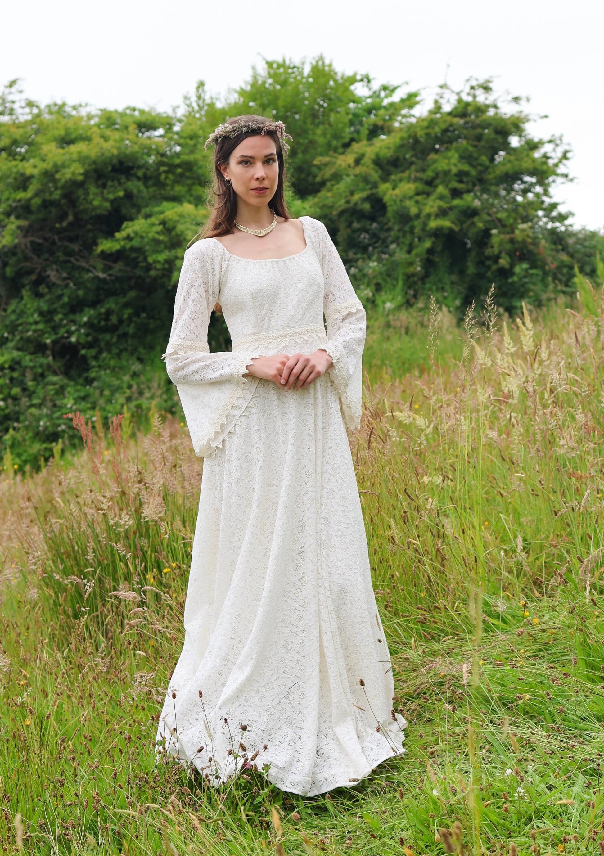 Sustainable cotton lace gown with bell sleeves, Bébhinn Boho Lace Wedding Dress shown outdoors in a meadow front view.
