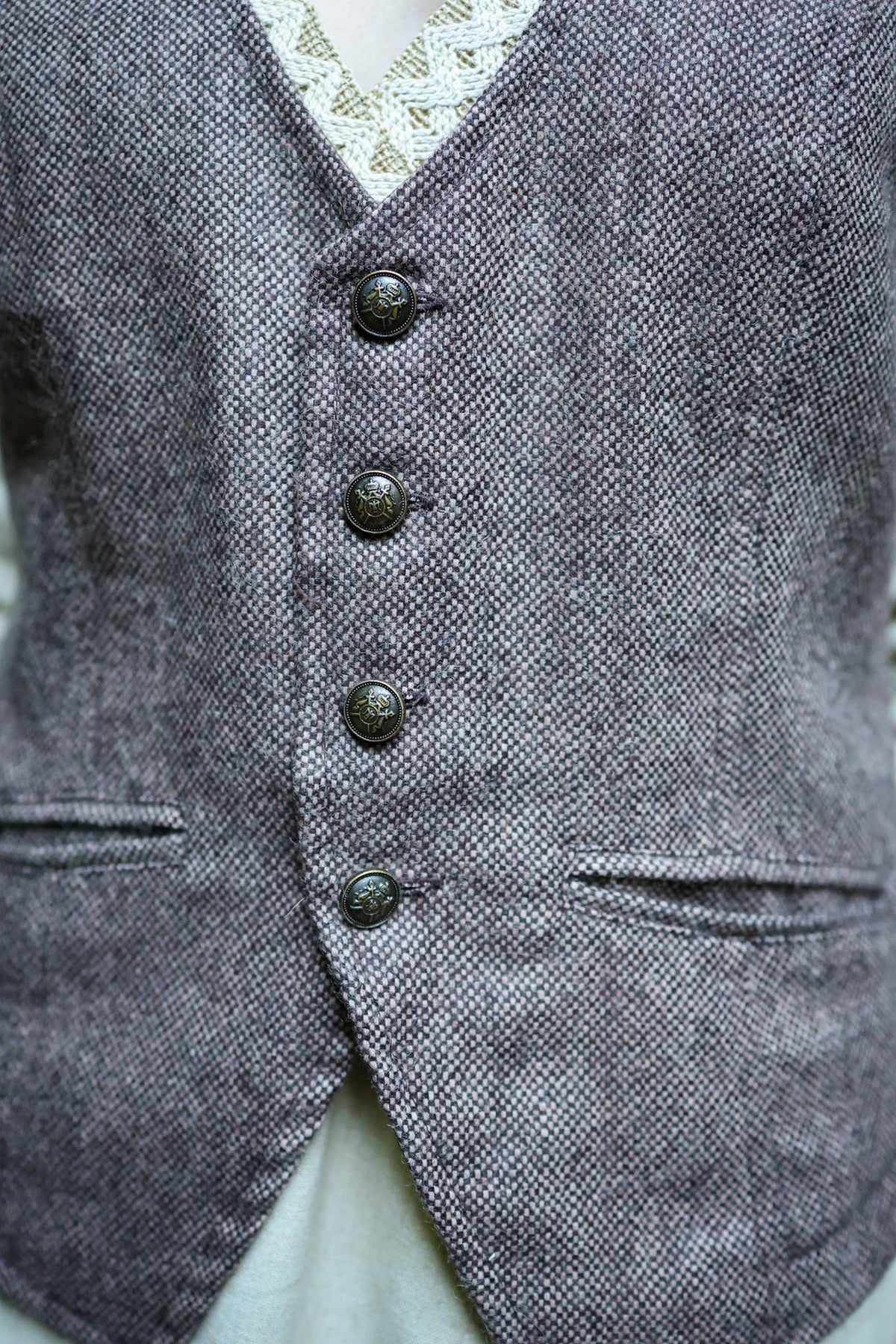 Close-up of earthy brown tweed waistcoat with tailored front, buttons and welt pockets
