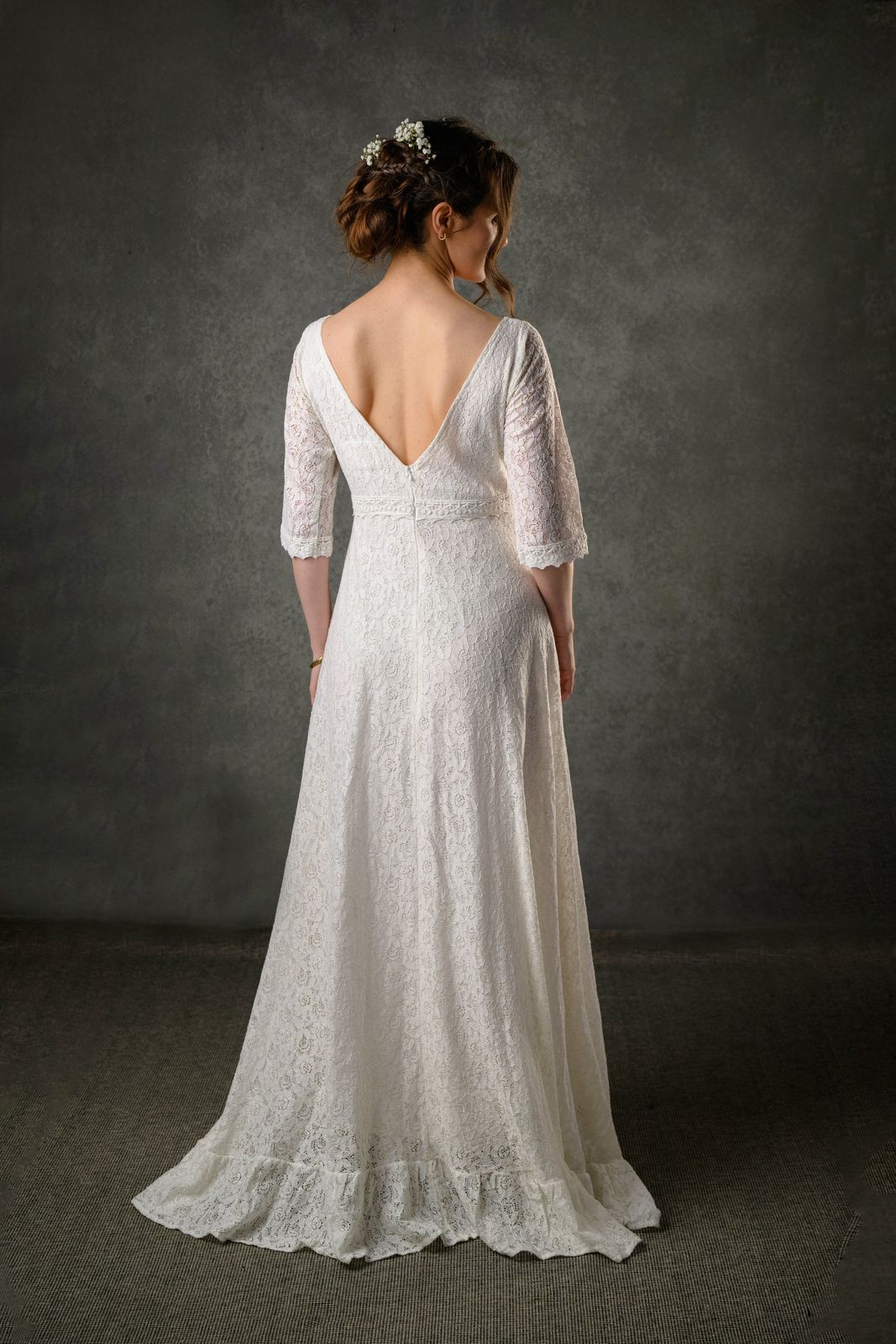 Back view of ivory lace Celtic wedding dress with deep V back, three quarter sleeves and flowing full-length skirt