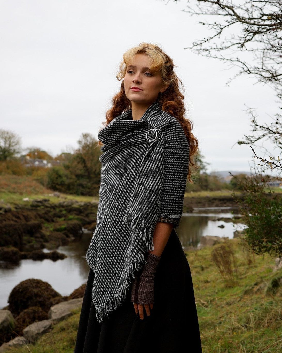Black and white wool blend shawl fastened with silver Celtic brooch in an Irish coastal setting designed by Celtic Fusion