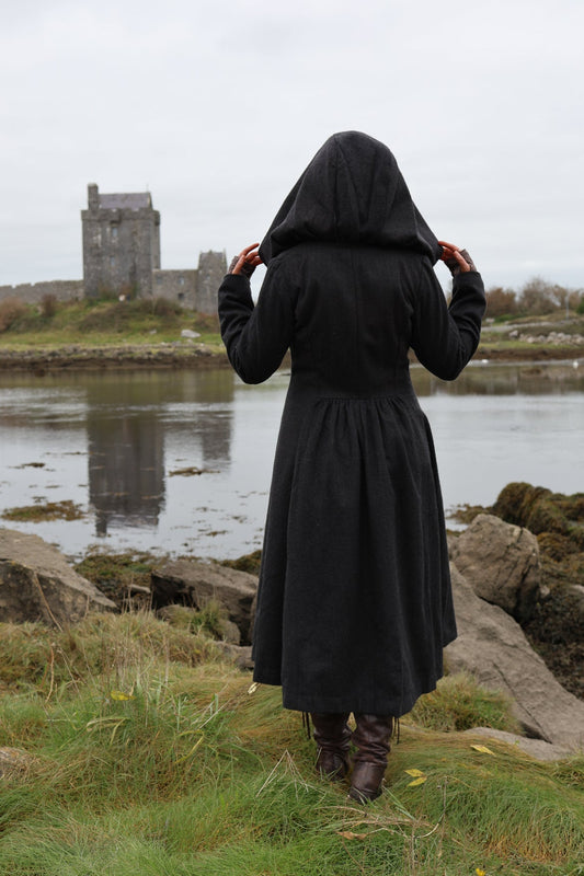 Back view of black gothic maxi wool coat showing oversized hood, fitted waist and full gathered skirt