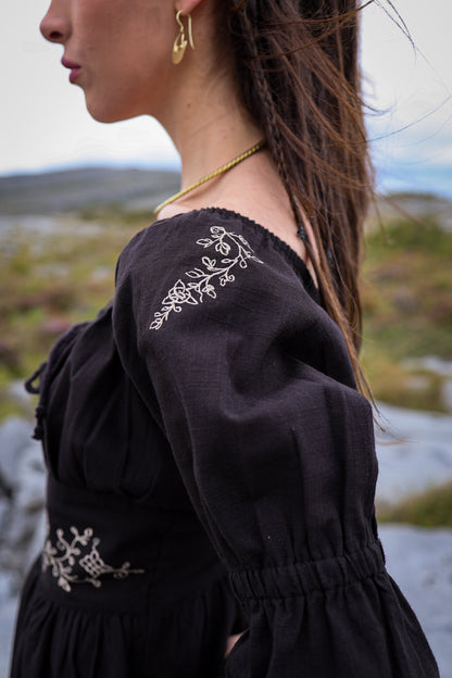  Close-up of the Fiadh black dress showing delicate botanical embroidery on the shoulder and gathered puff sleeve.