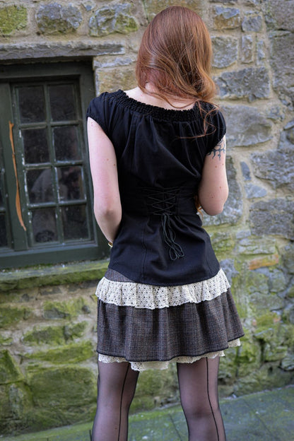 Back view of brown tweed mini skirt with layered cotton lace trim and separate shorts, worn low on the waist with a black fitted top.