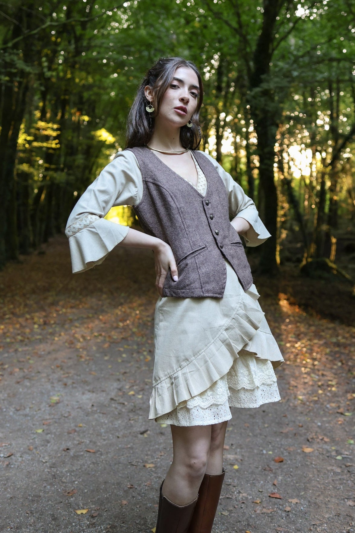 Woman wearing earthy brown fitted tweed waistcoat over cream folklore dress in woodland setting by Celtic Fusion Design