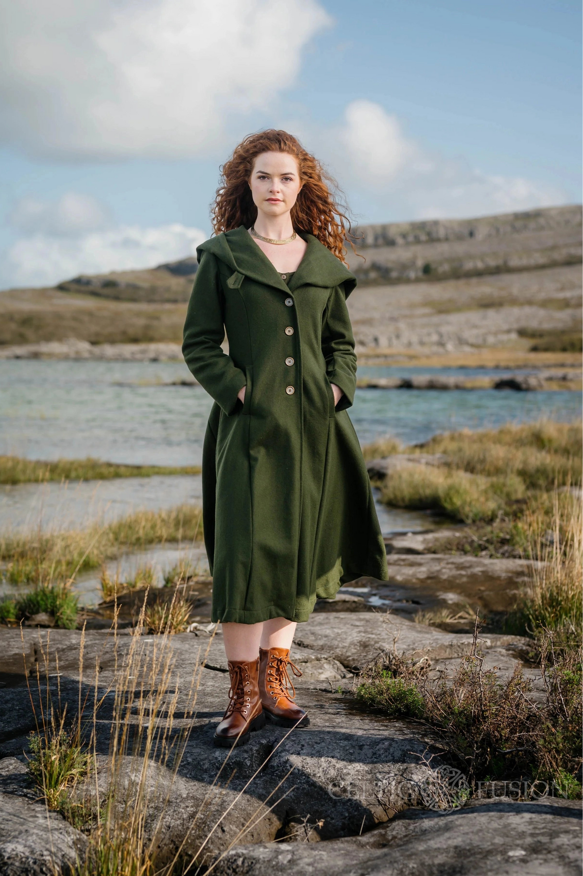 Woman wearing dark green long wool coat with large hood, button front and fitted feminine silhouette outdoors
