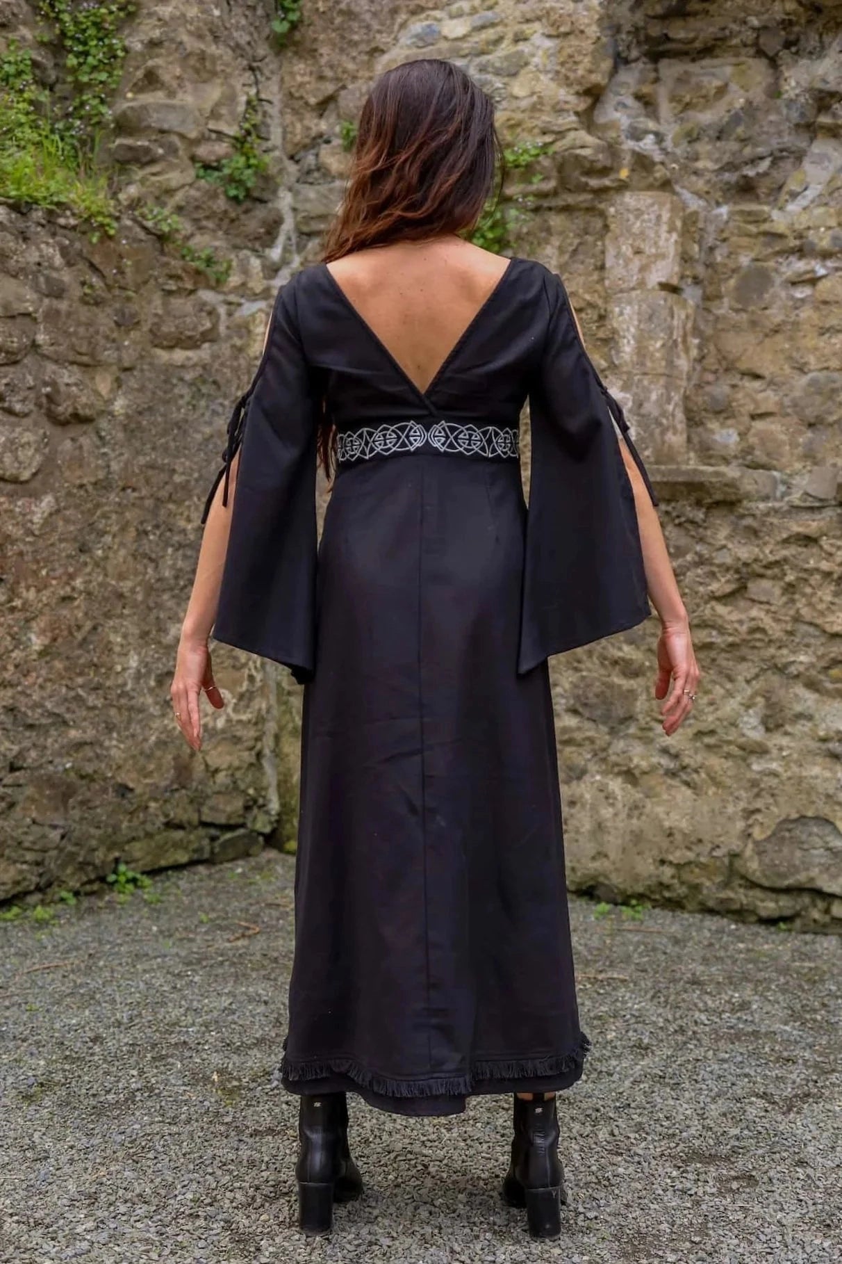 Back view of Maeve Black Celtic Dress, dark romantic dress with bell sleeves, plunging back and full length silhouette