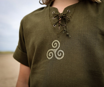 Close-up of green boys Celtic shirt showing embroidered Triskele symbol and traditional lace-up neckline.