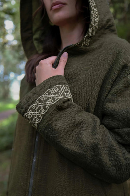 Close-up of olive green Celtic jacket showing embroidered knotwork detail on the cuff and hood edge.