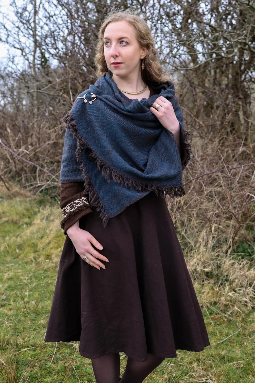 Irish-inspired black and turquoise shawl fastened with a copper brooch and styled for folklore wear