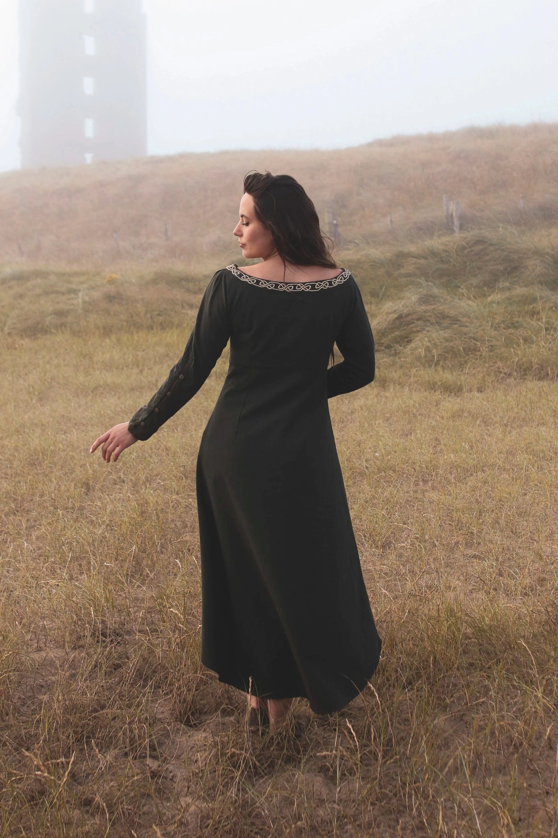 Back view of green Celtic dress with long sleeves and flowing silhouette, an alternative wedding guest dress with high low skirt and folklore styling.