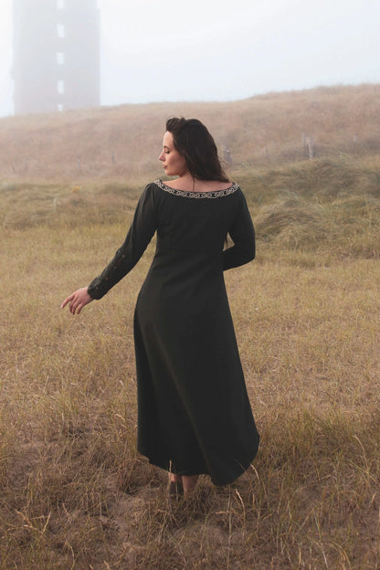 Back view of green Celtic dress with long sleeves and flowing silhouette, an alternative wedding guest dress with high low skirt and folklore styling.