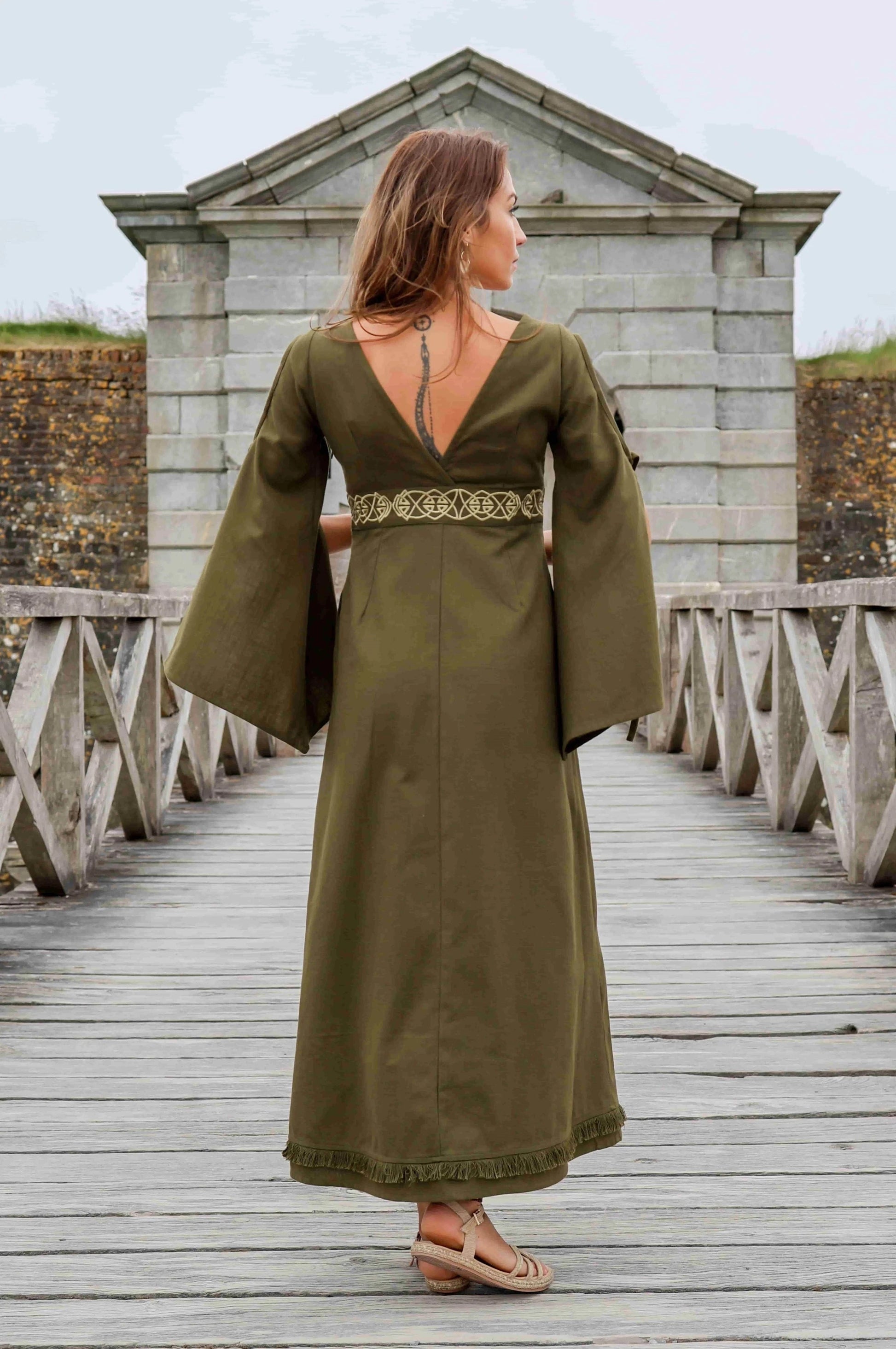 Back view of the Maeve Celtic Dress, green Celtic maxi dress with flowing bell sleeves, deep V back and embroidered Celtic waist detail.