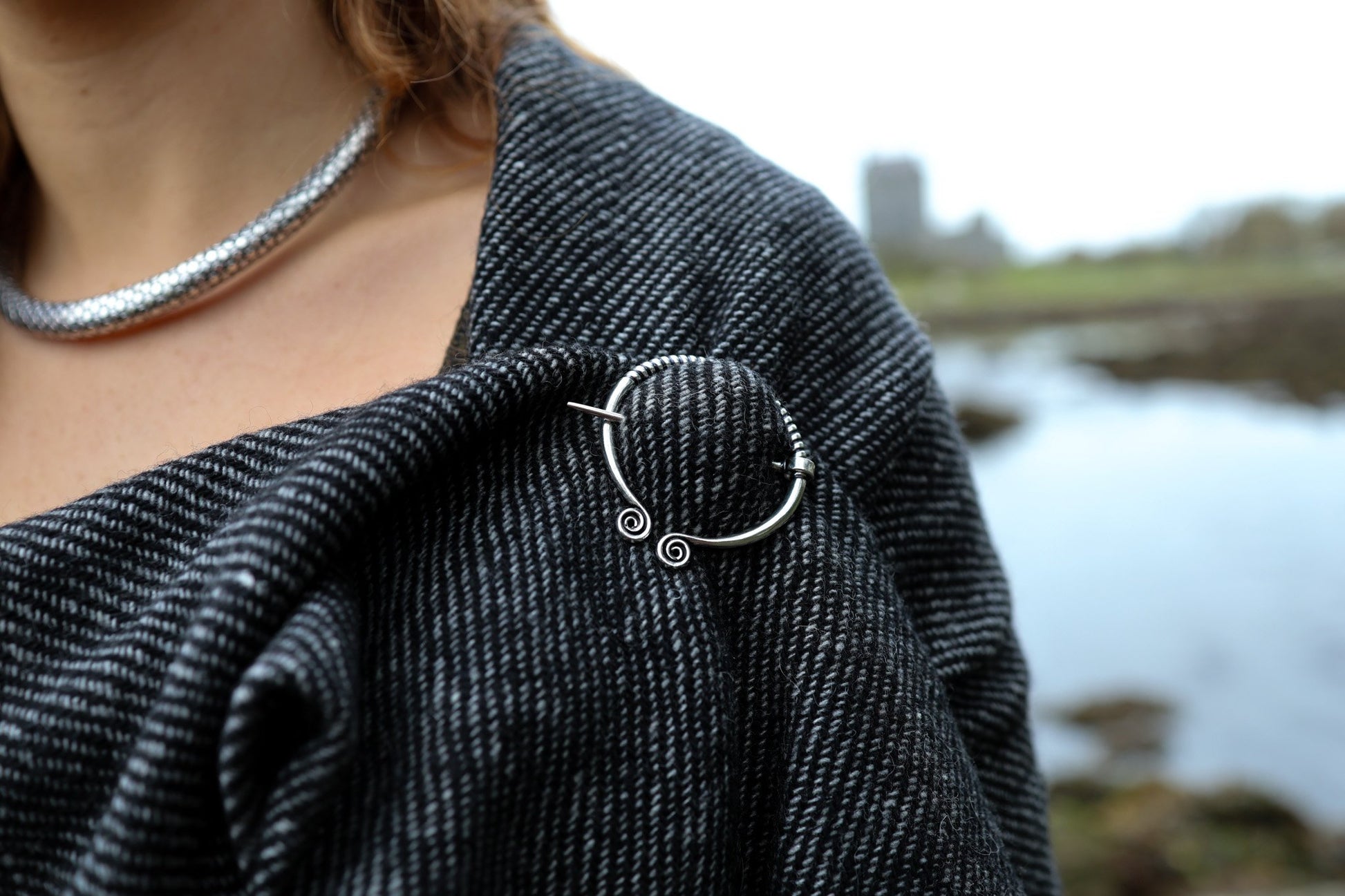 Detail of handwoven Celtic shawl with silver-tone white metal Uisneach brooch and textured shawl weave