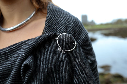 Detail of handwoven Celtic shawl with silver-tone white metal Uisneach brooch and textured shawl weave