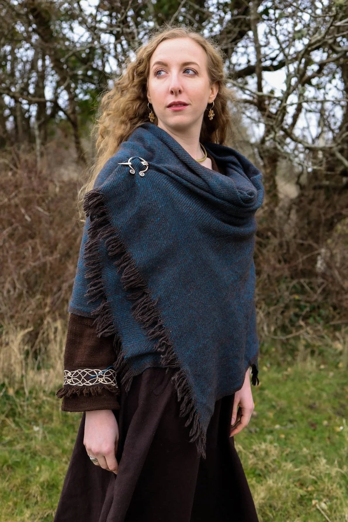 Black and turquoise handwoven shawl styled with Uisneach copper brooch in a woodland setting