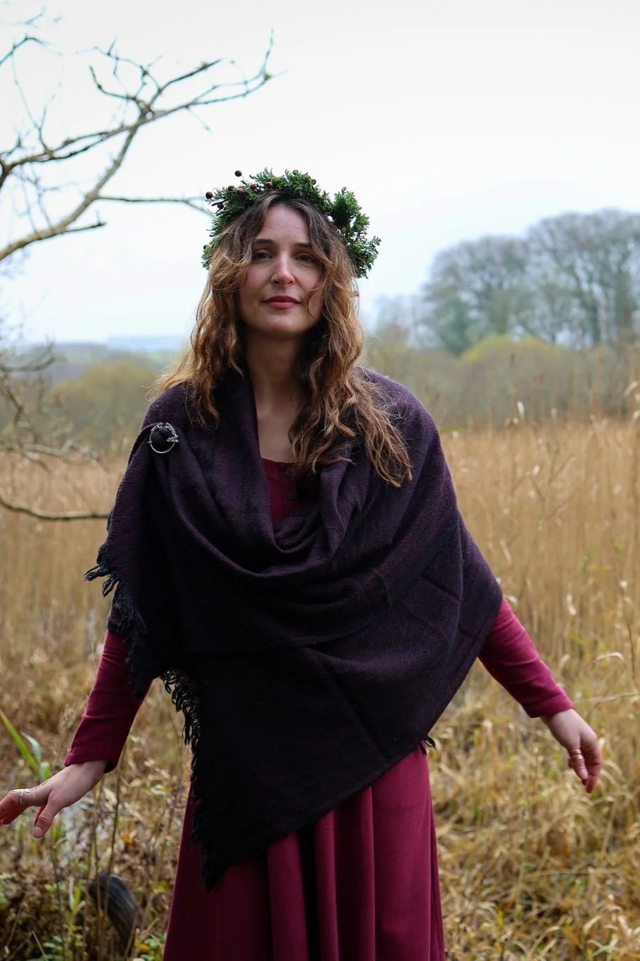 Soft maroon and black handwoven wool shawl with silver Trinity brooch and fringe detail worn outdoors