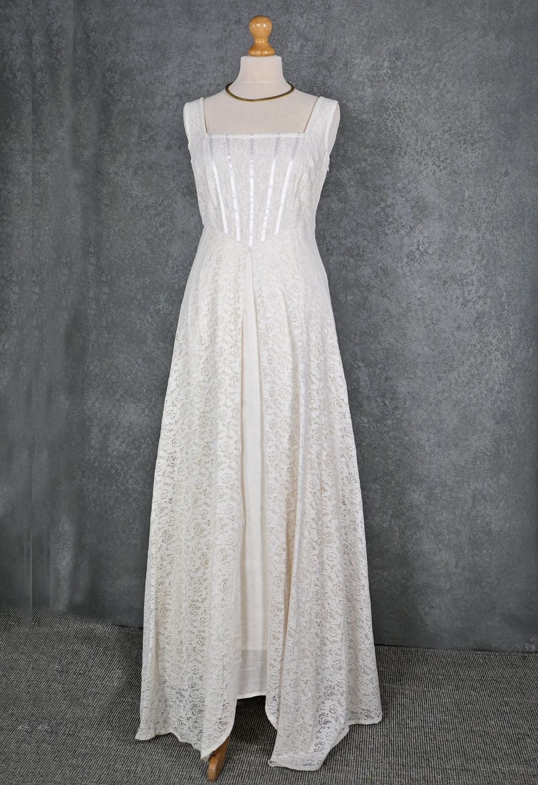 Ivory lace Celtic bridal gown on mannequin with square neckline, structured bodice and full-length layered skirt
