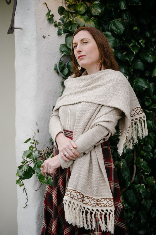 Beige woven natural cotton stole with fringed edges and Celtic-inspired trim styled as a layered shawl