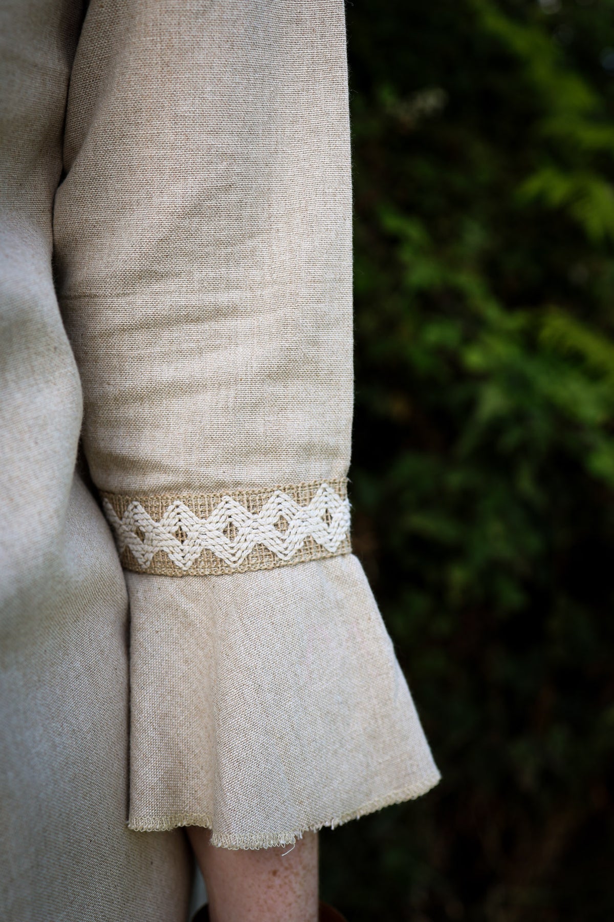 Close-up of natural linen bell sleeve with handwoven jute trim and softly flared frill cuff.