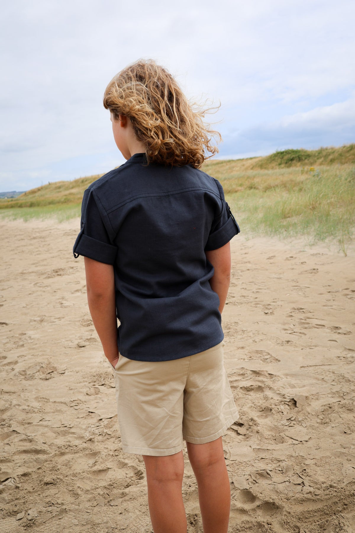 Back view of navy boys medieval shirt showing relaxed fit and roll-up sleeves