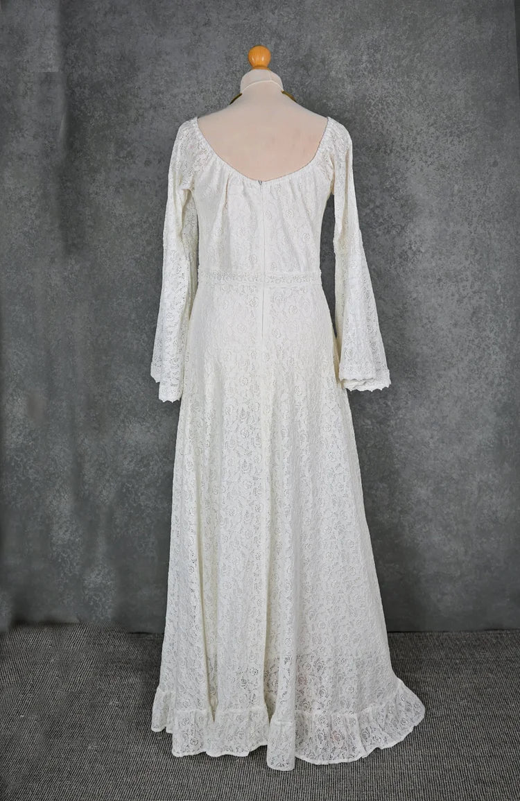 Rear view of off-white lace boho wedding dress on mannequin with low scoop back, full-length skirt, and delicate bell sleeve shape
