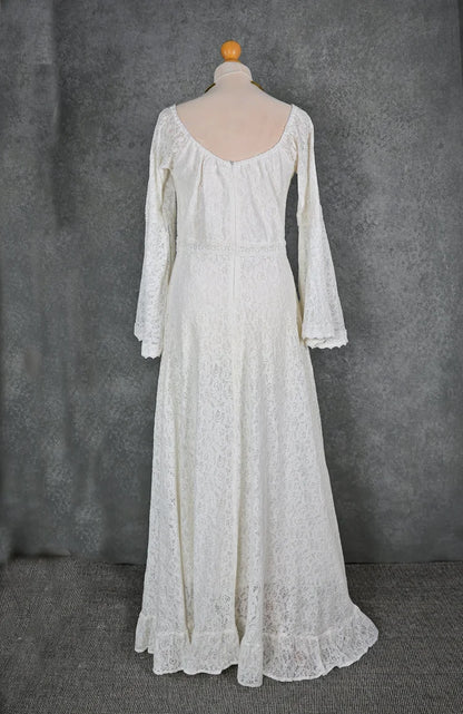 Rear view of off-white lace boho wedding dress on mannequin with low scoop back, full-length skirt, and delicate bell sleeve shape