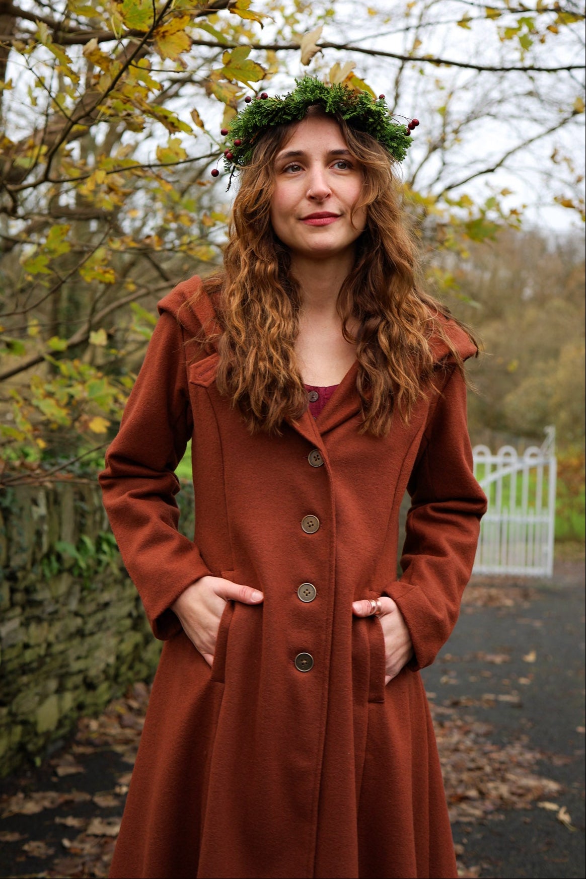 Close-up of rust autumn wool coat showing fitted waist, button front, pockets and rich burnt red colour. Folklore clothing by Celtic Fusion Design