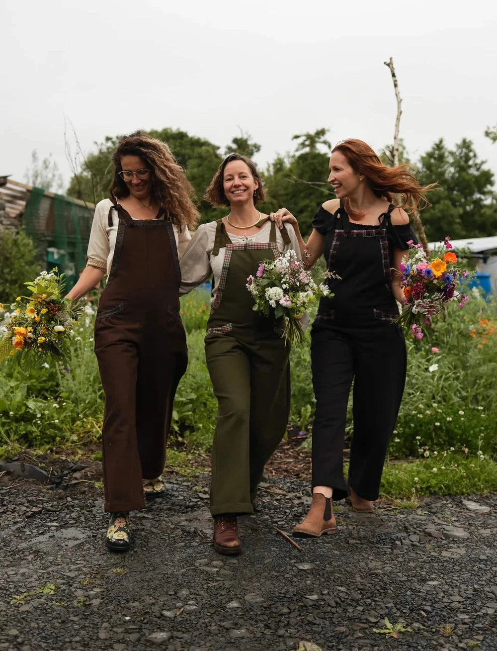 Three women wearing Celtic Fusion dungarees with pockets and tweed details available in green, brown and black