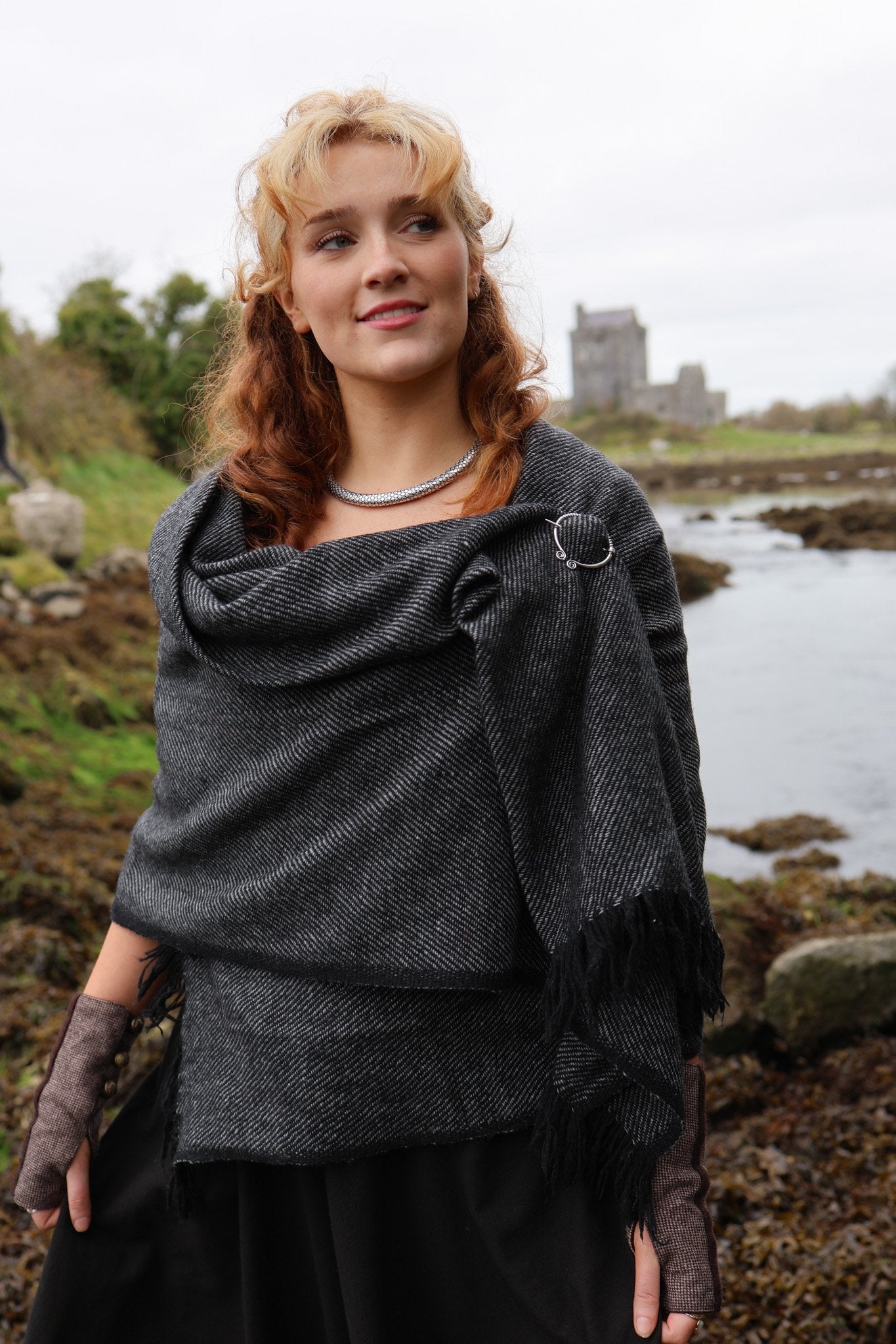 Handwoven Celtic shawl with white metal silver Uisneach brooch worn as an elegant layered wrap outdoors